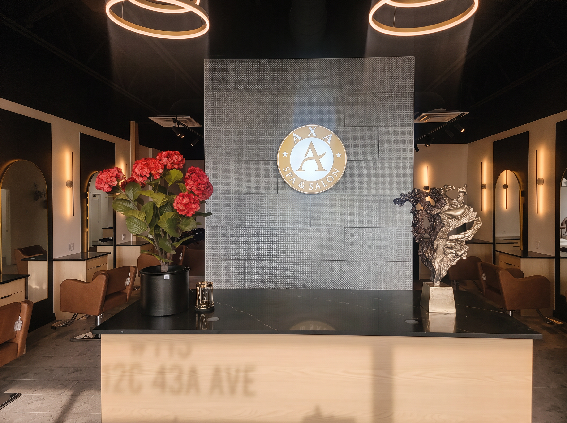 AXA Spa & Salon reception with the gold AXA emblem, fresh flowers and warm arched mirrors