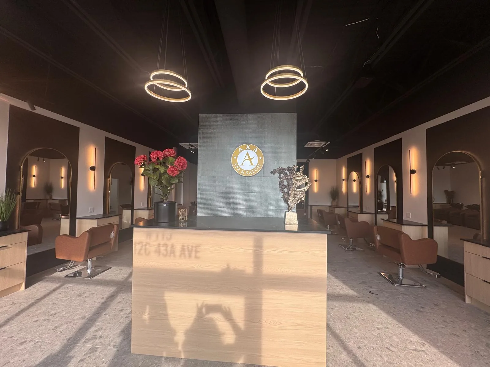 The AXA Spa & Salon reception, with the gold AXA emblem lit between two ring pendant lights